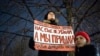 In November 2019, a woman in Moscow holds a banner that demands Russia adopt a law against domestic violence. "They haven't killed us yet," the poster reads. 