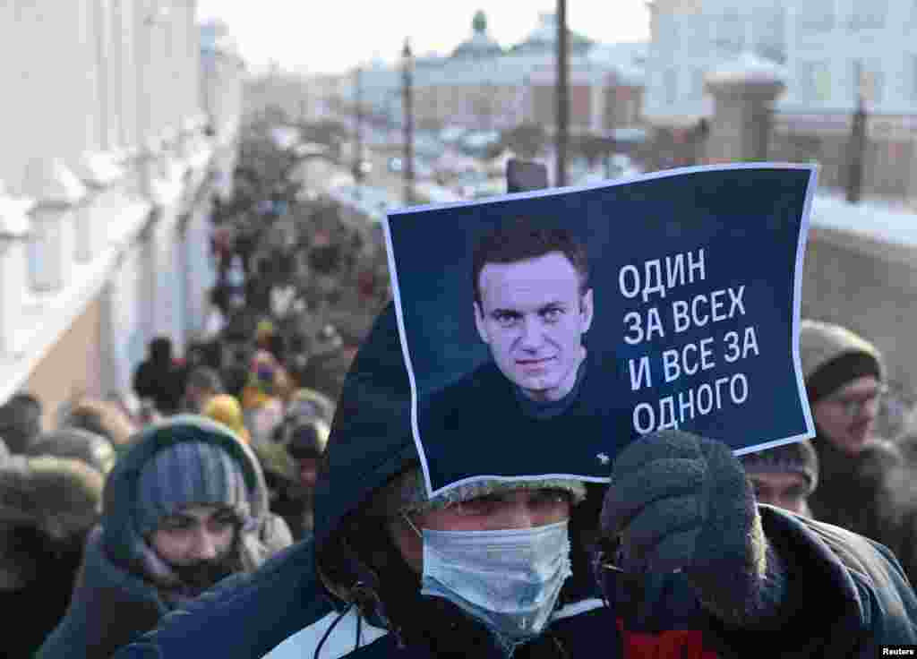 In Omsk, a man holds a placard with Aleksei Navalny's photo and the slogan "All for one and one for all." 