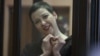 Belarusian opposition activist Maryya Kalesnikava, charged with extremism and trying to seize power illegally, forms a heart shape with her hands inside a defendants' cage during her September 6, 2021 court hearing in Minsk. 