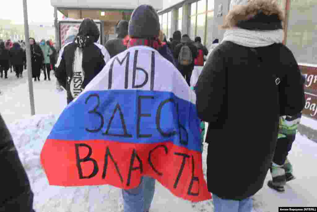 A protester in Novosibirsk wears a Russian flag with the slogan "We're in charge here." 