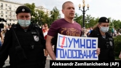 Moscow police detain an opposition activist with a poster reading "Smart Voting" during an anti- COVID-19 vaccination protest in the Russian capital on August 14, 2021.