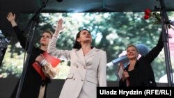 Belarusian presidential candidate Svyatlana Tsikhanouskaya, flanked by allies Veranika Tsapkala (left) and Maryya Kalesnikava, addresses her July 30 rally in Minsk.