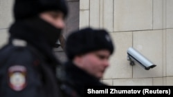 Police officers walk past a surveillance camera in downtown Moscow on January 26, 2020. 